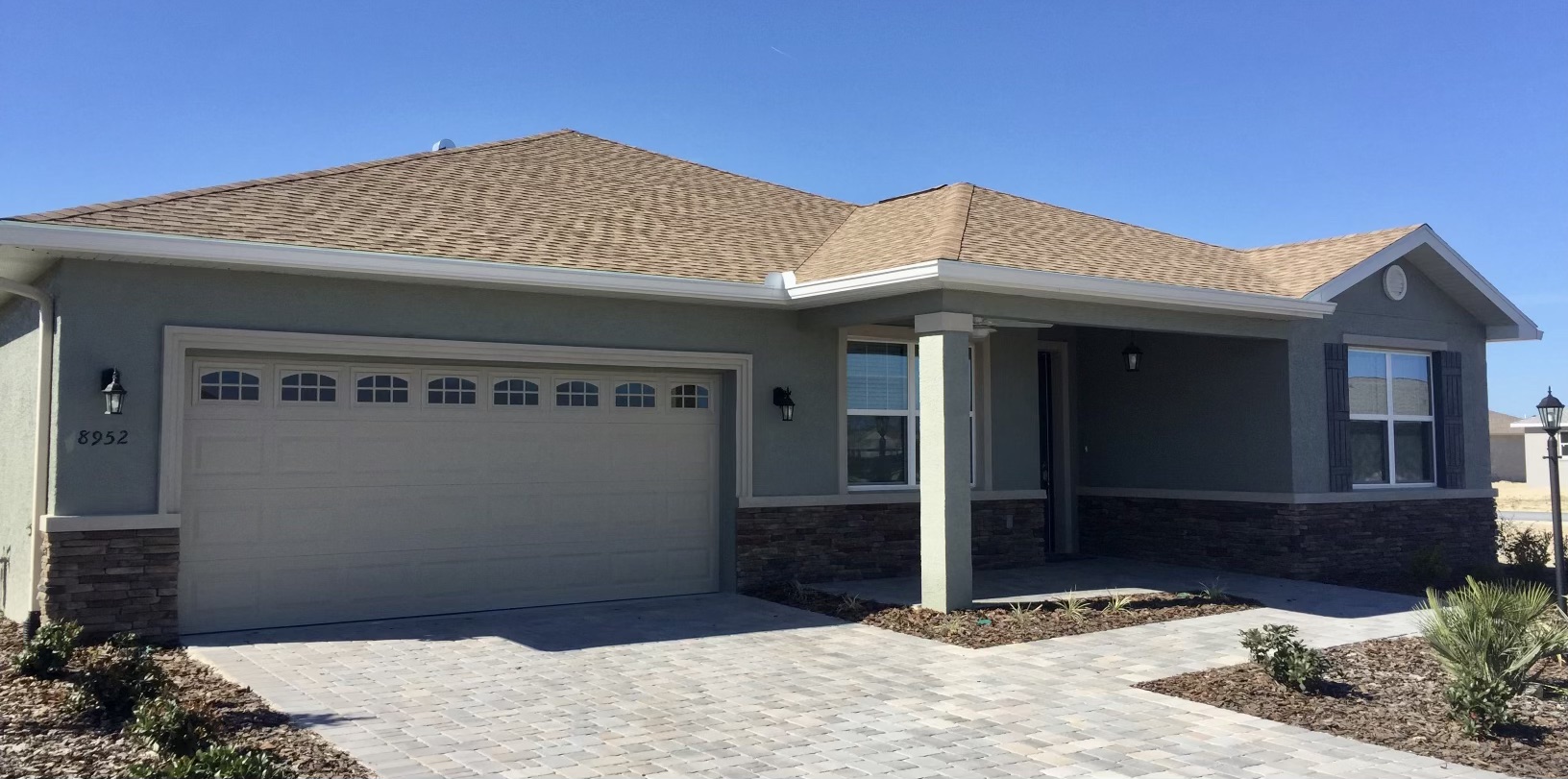 Tan stucco home with seamless gutters wrapping the hip roof