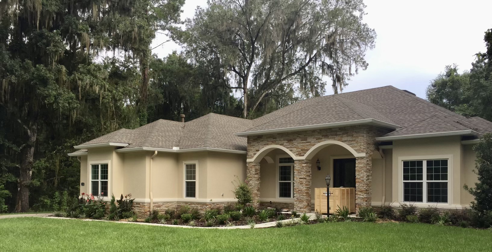 Stone-accented home with seamless gutters under oak trees